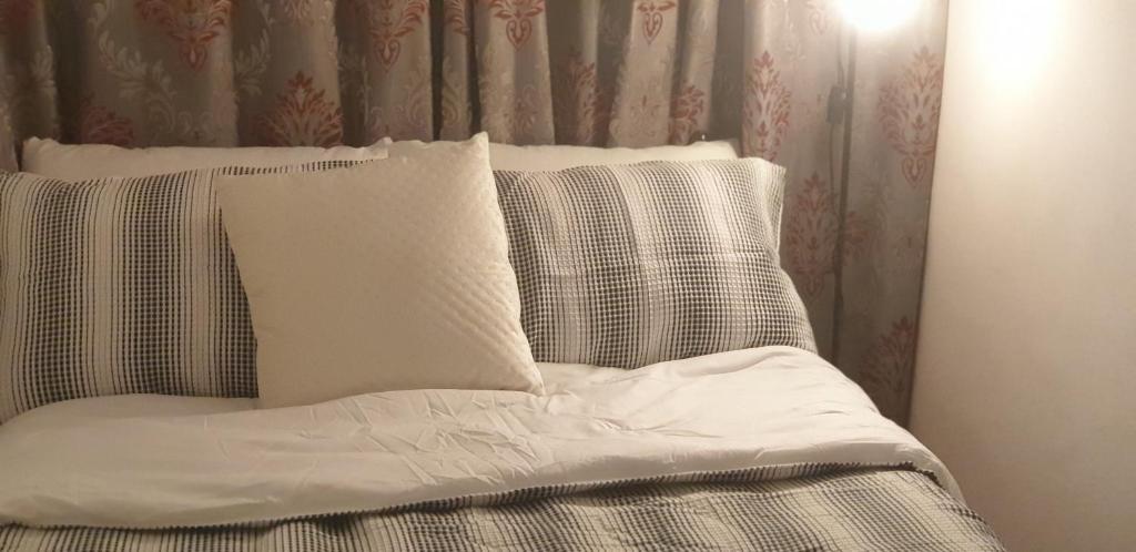 Bett mit weißer Bettwäsche und Kissen in einem Zimmer in der Unterkunft Tanih Place in Abu Dhabi