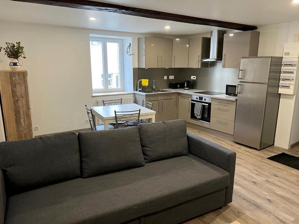 a living room with a couch and a kitchen at Bel appartement T3 proximité centre et commerces in Pélussin
