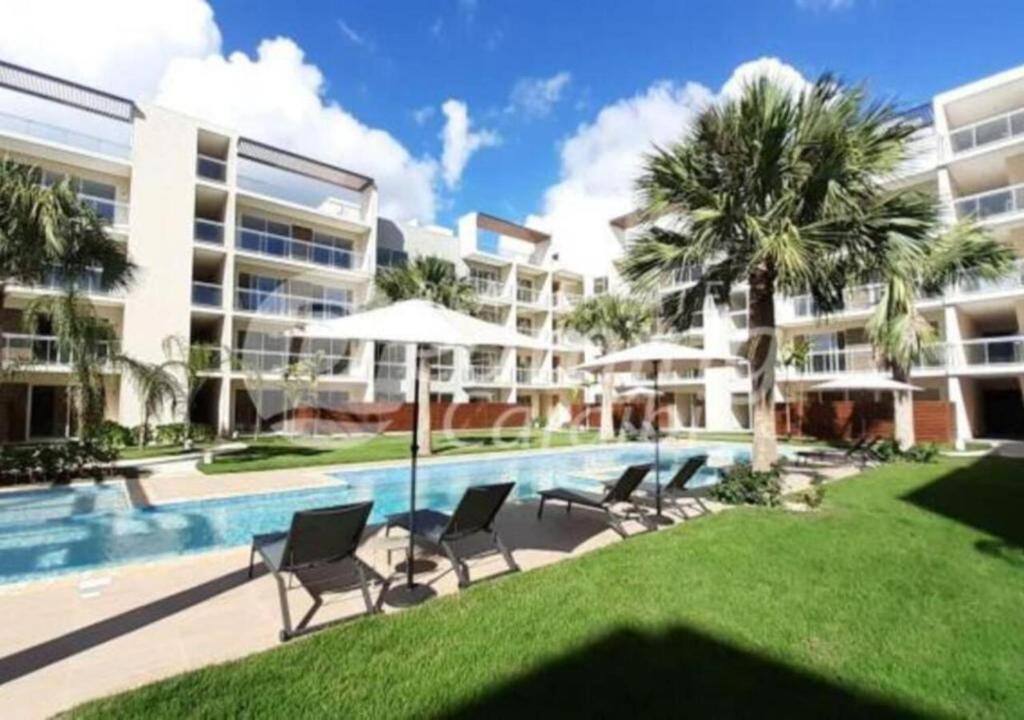 a resort pool with chairs and umbrellas and palm trees at Residence Vibe Dominicus 308 in Bayahibe