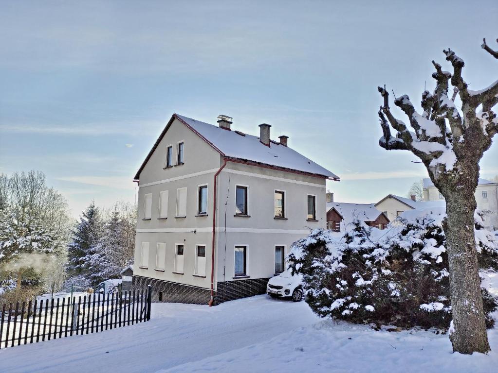 Une grande maison blanche avec de la neige au sol dans l'établissement Apartmány U Floriánů, à Žacléř