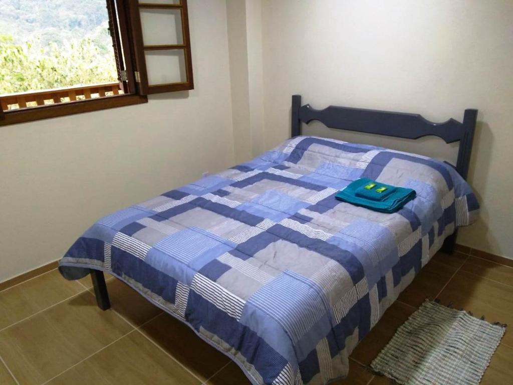 uma cama azul e branca num quarto com uma janela em Casa Verde da Floresta da Gávea em Visconde de Mauá