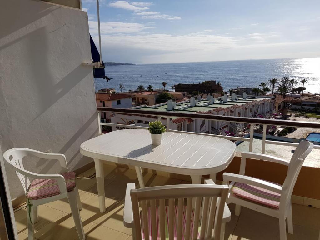 una mesa blanca y sillas en un balcón con vistas al océano en Terraza al Teide, en Punta del Hidalgo