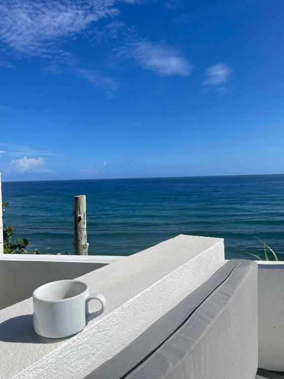 una tazza di caffè seduta su un cornicione che si affaccia sull'oceano di The Sea Cliff Hotel Resort & Spa a Port Antonio