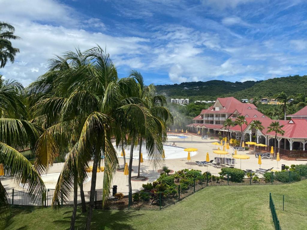 a view of a resort with a pool and palm trees at Olivera Studio P&V Ste luce in Sainte-Luce