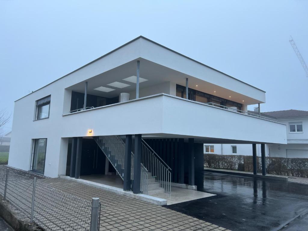 - un bâtiment blanc avec un escalier devant dans l'établissement Haus Am Anger Dornbirn, à Dornbirn
