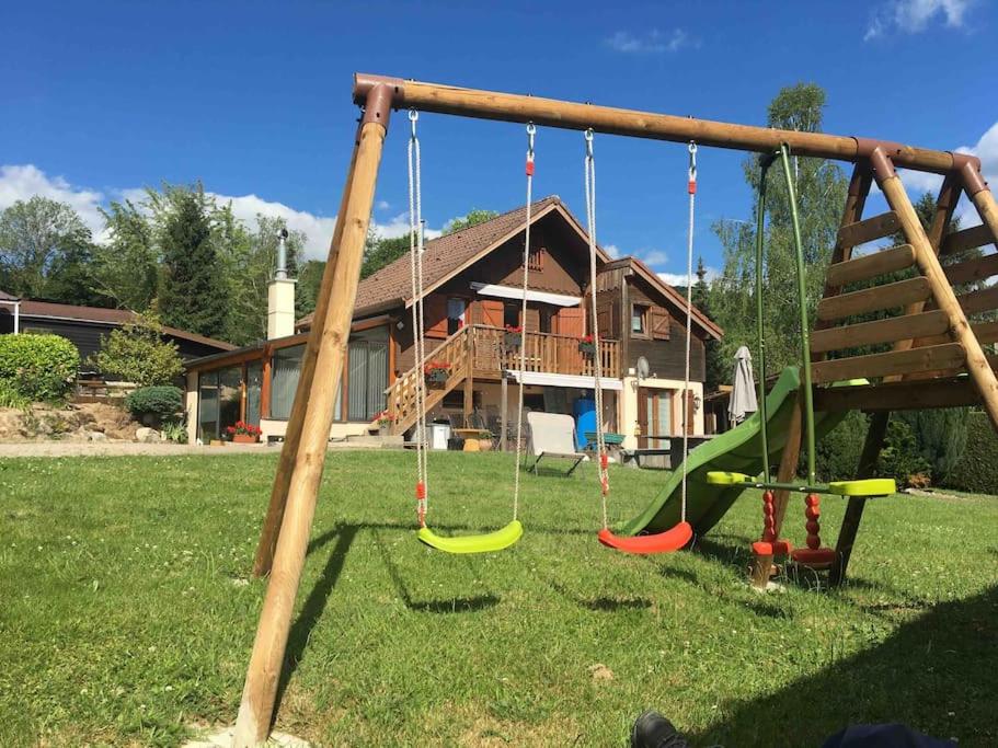a playground with swings in front of a house at Le Chalet de la REPANDISE in Laveline-du-Houx
