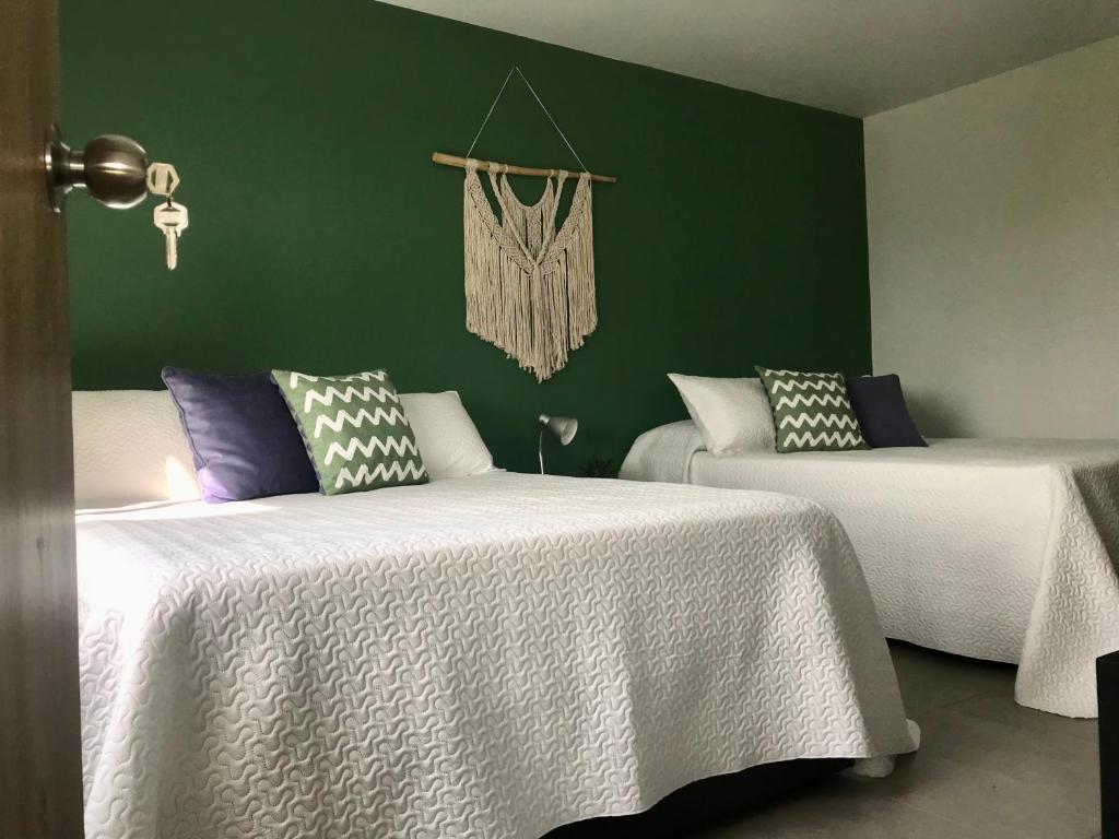 two beds in a room with green walls at Torcaza Casa de Campo in Quimbaya