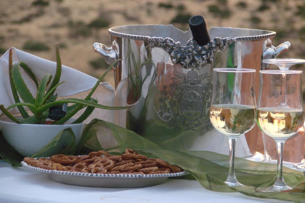 a table with glasses of wine and a plate of food at Beenbreck Guest Farm in Windhoek Noord