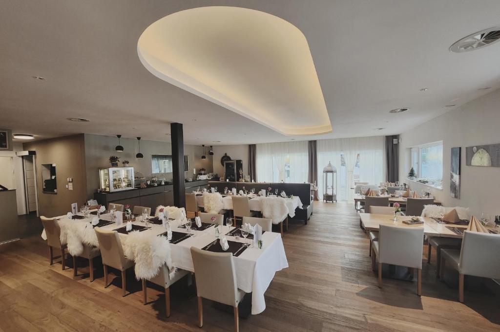 a restaurant with white tables and chairs in a room at Pension fein & sein in Schwarzsee