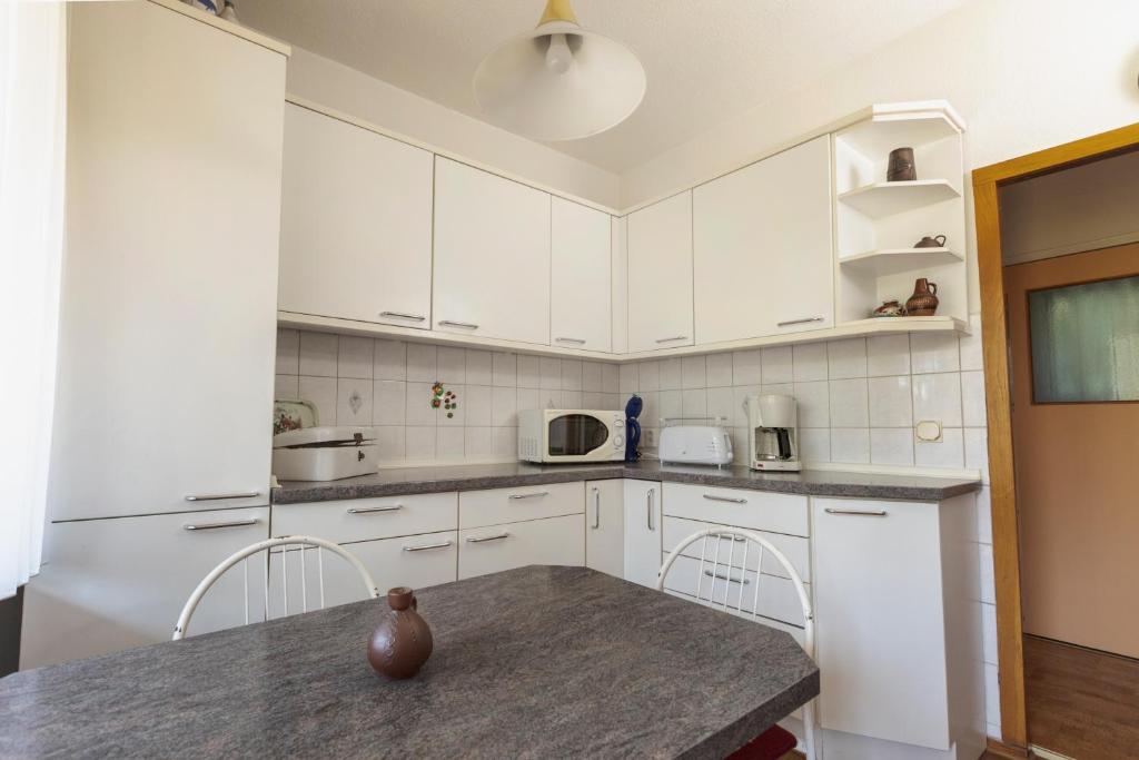 a kitchen with white cabinets and a table with chairs at Ferienhaus Annerose in Wendisch Rietz