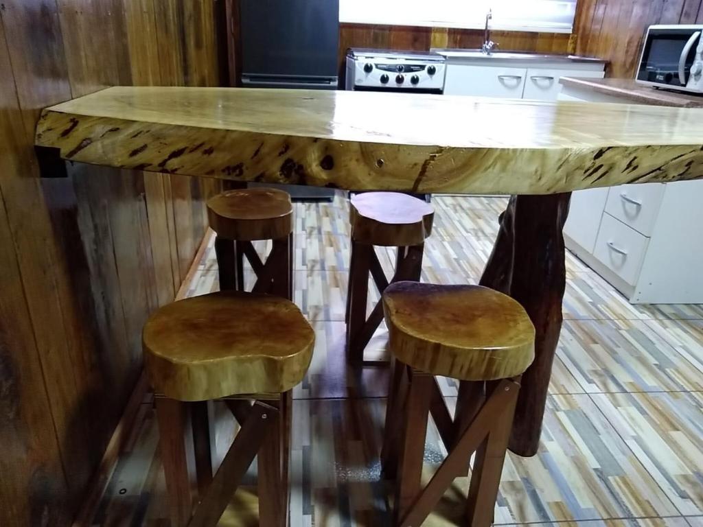 a kitchen with a large wooden table with two stools at Cabañas El_Nativo2 in Choshuenco