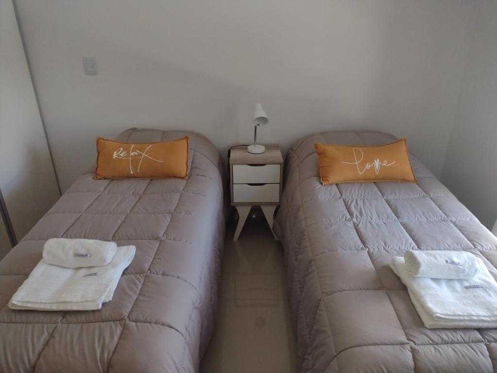 Habitación pequeña con 2 camas y una mesita de noche en Departamento Caleta View en Puerto Madryn