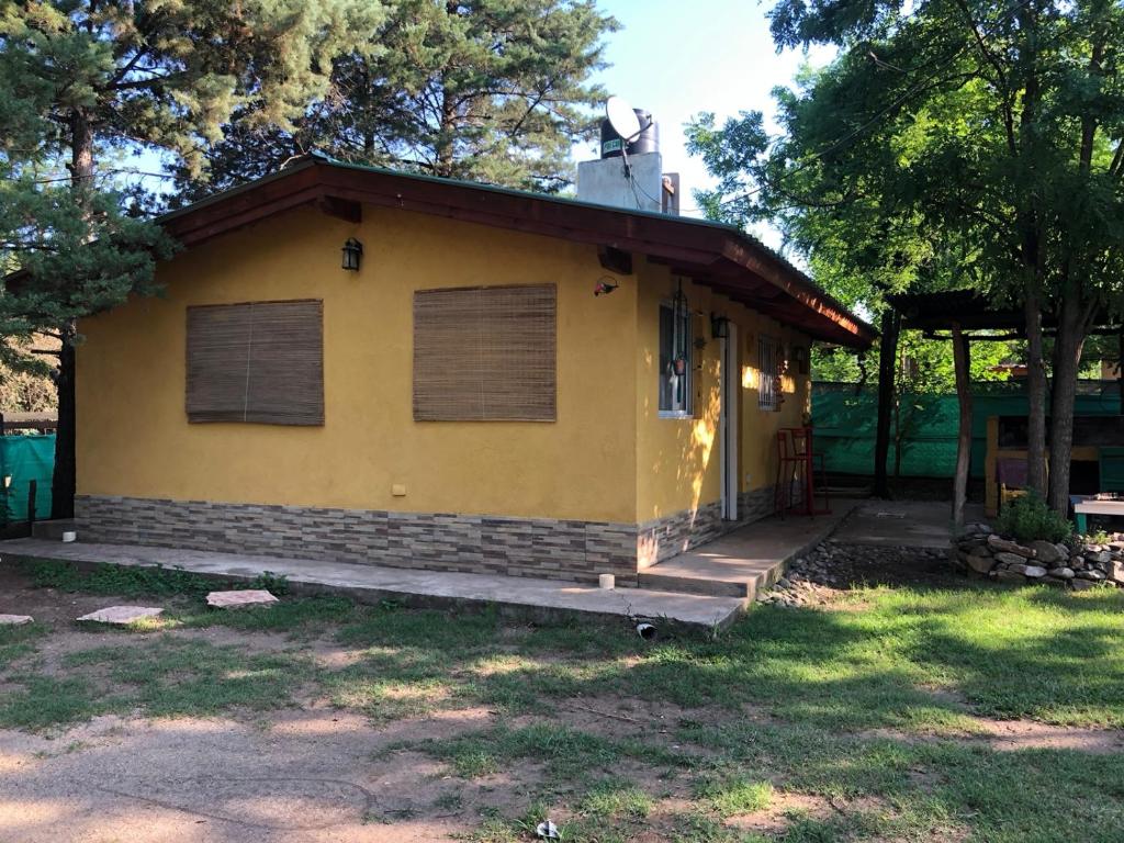 una pequeña casa amarilla con porche en Cabaña Hakuna Matata en Santa Rosa de Calamuchita