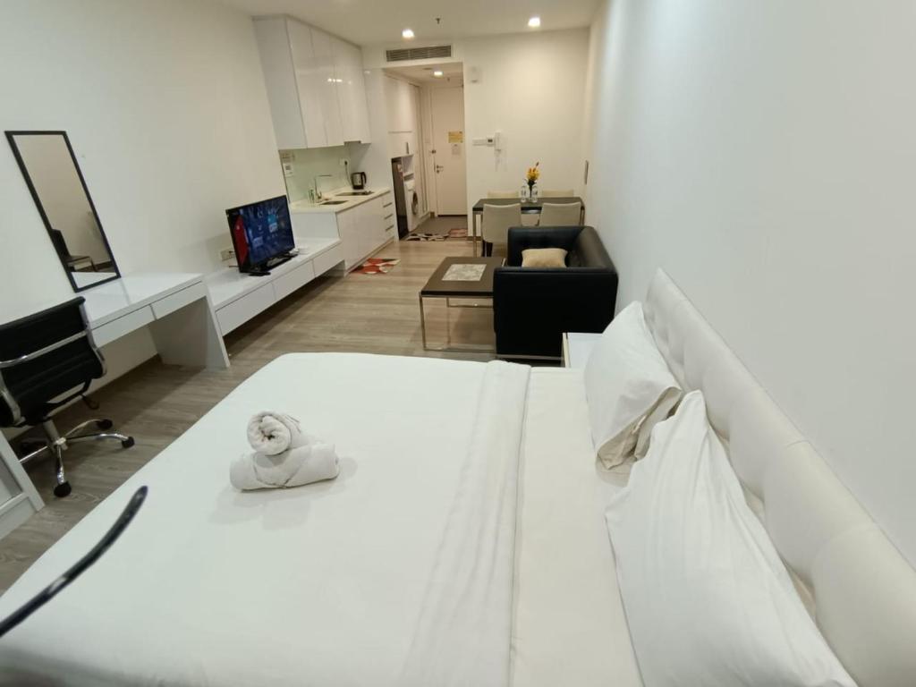 a bedroom with a white bed and a living room at The Perfect Retreat @One Bukit Ceylon (UNIT 25-2) in Kuala Lumpur