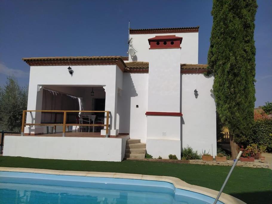 una casa blanca con piscina frente a ella en Agradable casa con piscina en la serranía., en Arriate