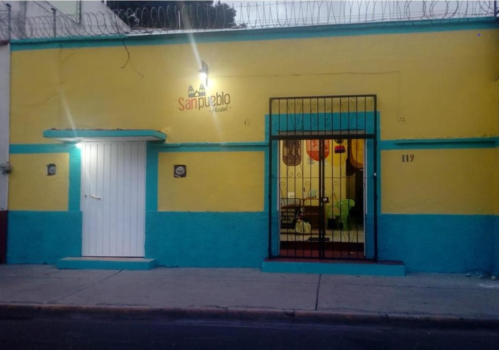 a yellow and blue building with a gate in front of it at Hostal San Pueblo in Oaxaca City