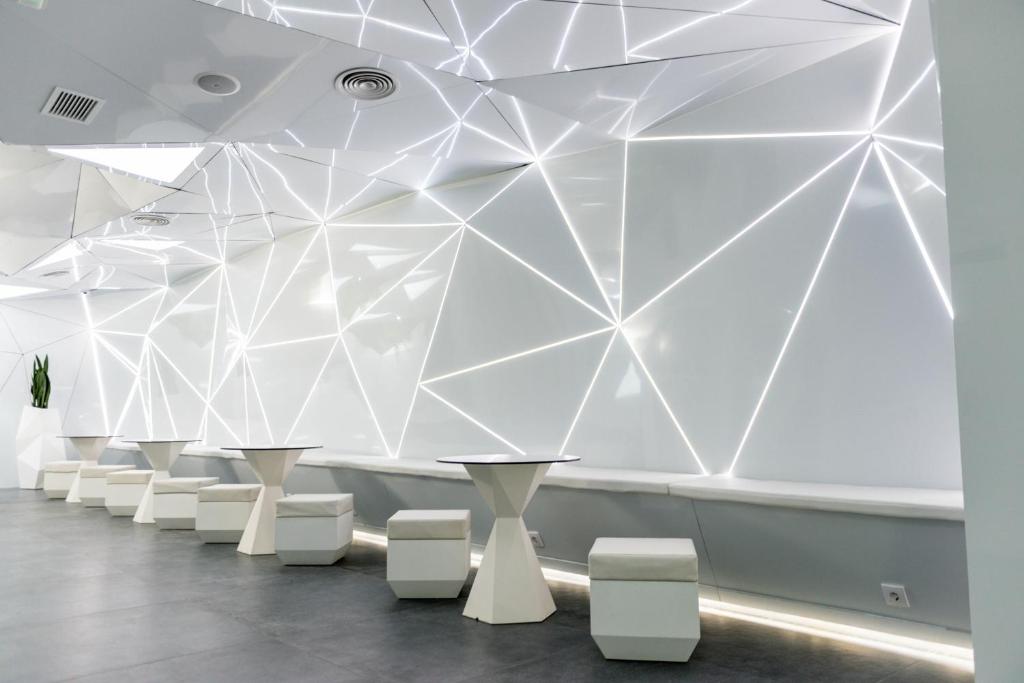 una stanza con tavoli bianchi e sgabelli bianchi di Optimi Rooms Madrid a Madrid