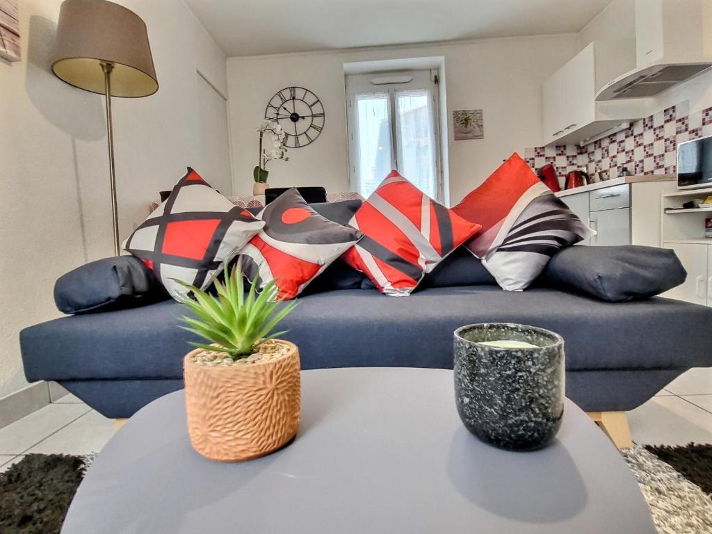 a living room with a blue couch with colorful pillows at Superbe Type 2 - Cosy et Chaleureux in Bouguenais