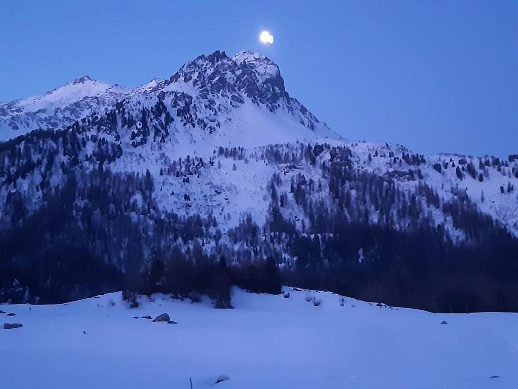 una montaña cubierta de nieve con la luna en el cielo en Lovely 3 Bedroom Apt., en Maloja