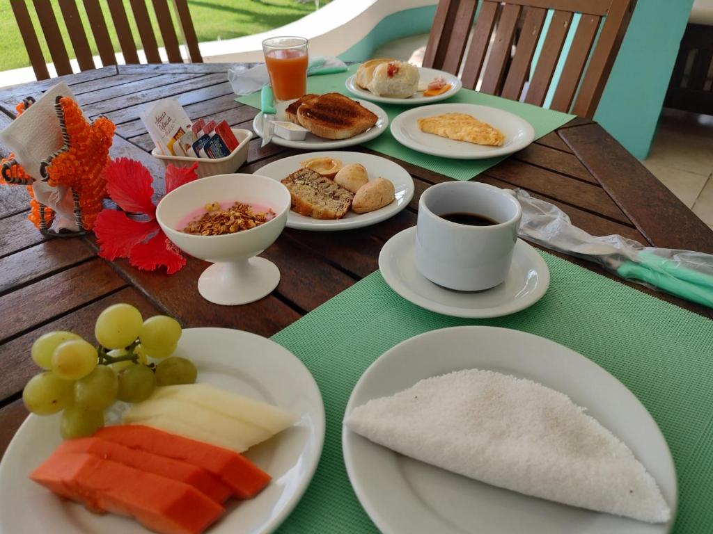 una mesa con platos de comida y una taza de café en Villa Caracol, en Porto de Galinhas