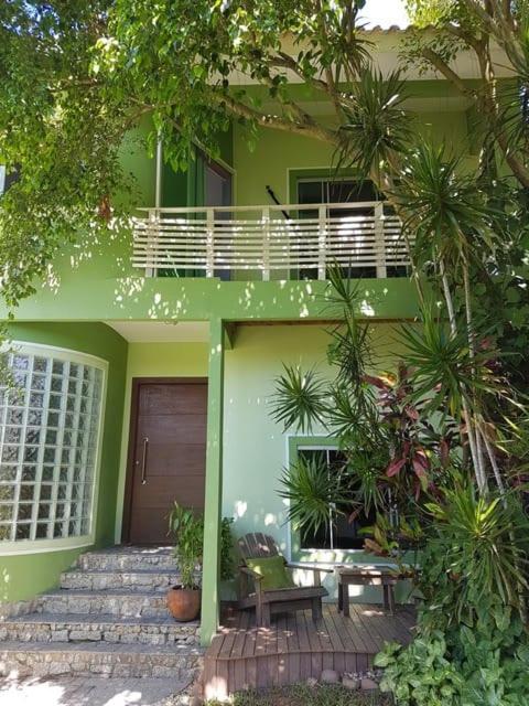 una casa verde con porche y escaleras delante en Casa Samauma Aluguel de Quartos en Florianópolis
