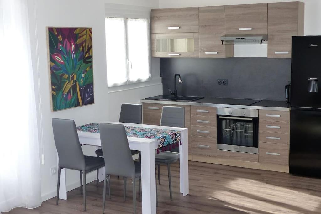 a kitchen with a white table with chairs and a stove at L'Escale n°5 in Tartas