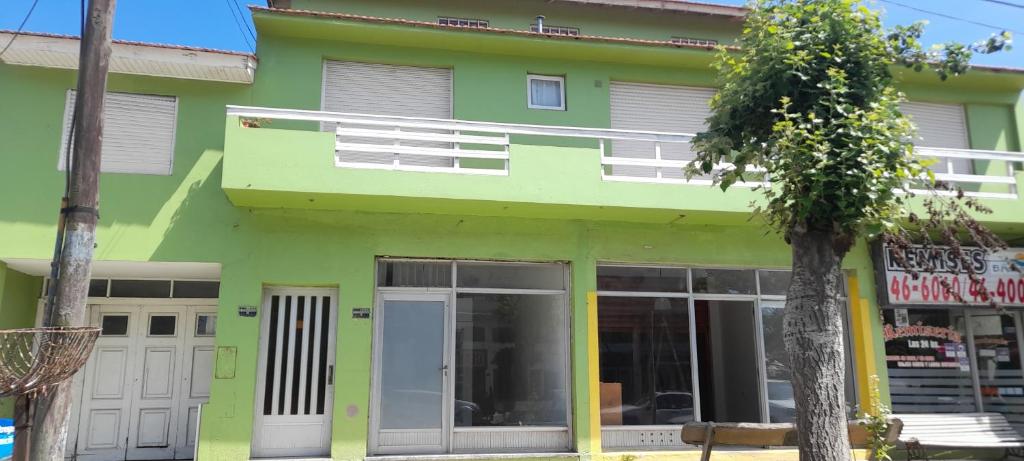 a green building with a tree in front of it at Tineo in Villa Gesell