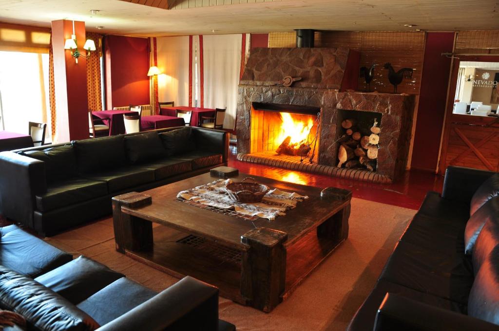 a living room with a fireplace and a couch and a table at Hotel y Cabañas del Nevado in Caviahue