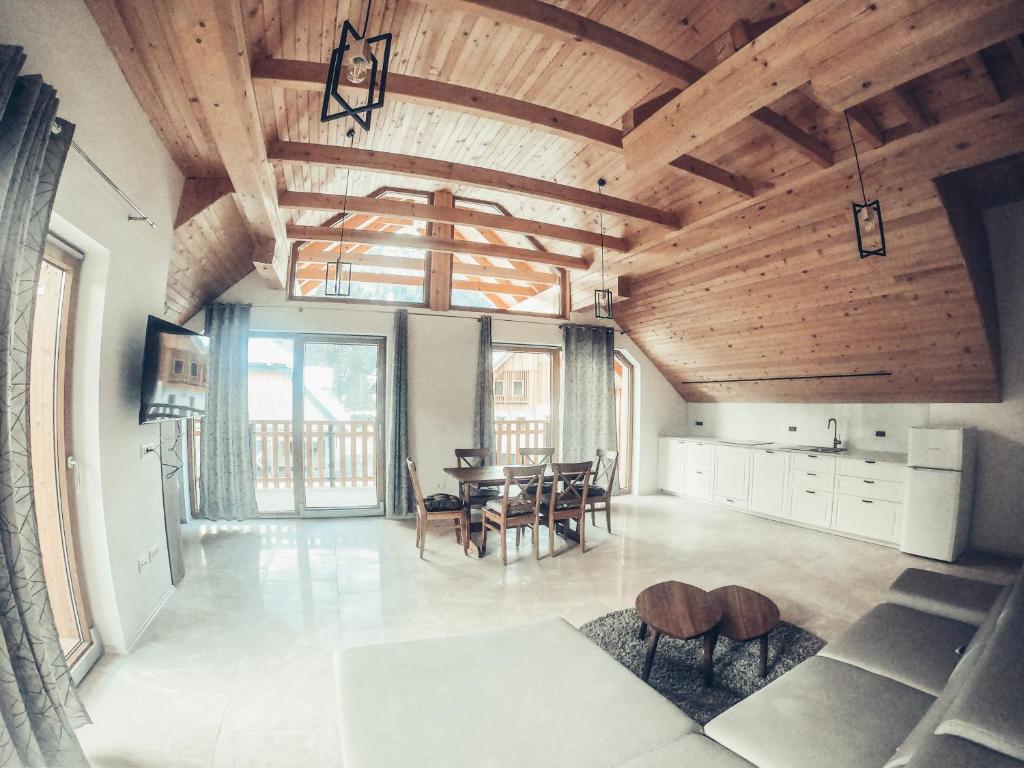 a kitchen and dining room with a wooden ceiling at ALPS Apartments in Kranjska Gora