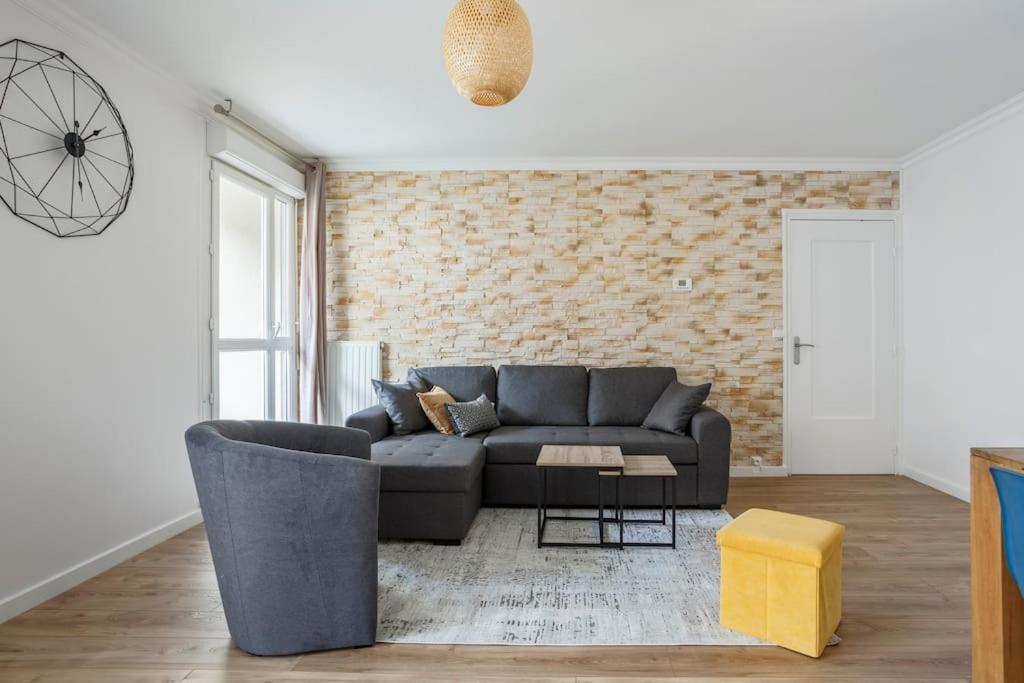 - un salon avec un canapé et un mur en briques dans l'établissement Appart spacieux près de la Seine, à Sartrouville