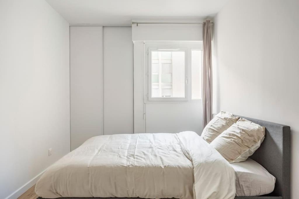 a white bedroom with a bed and a window at Appart spacieux près de la Seine in Sartrouville