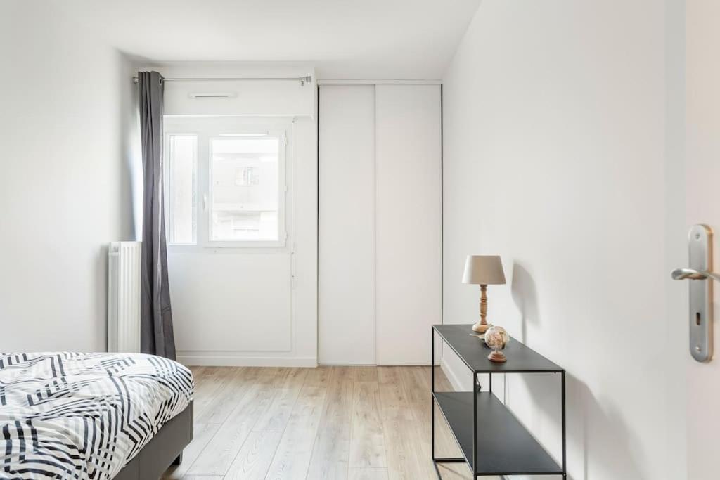 a bedroom with a bed and a table with a lamp at Appart spacieux près de la Seine in Sartrouville