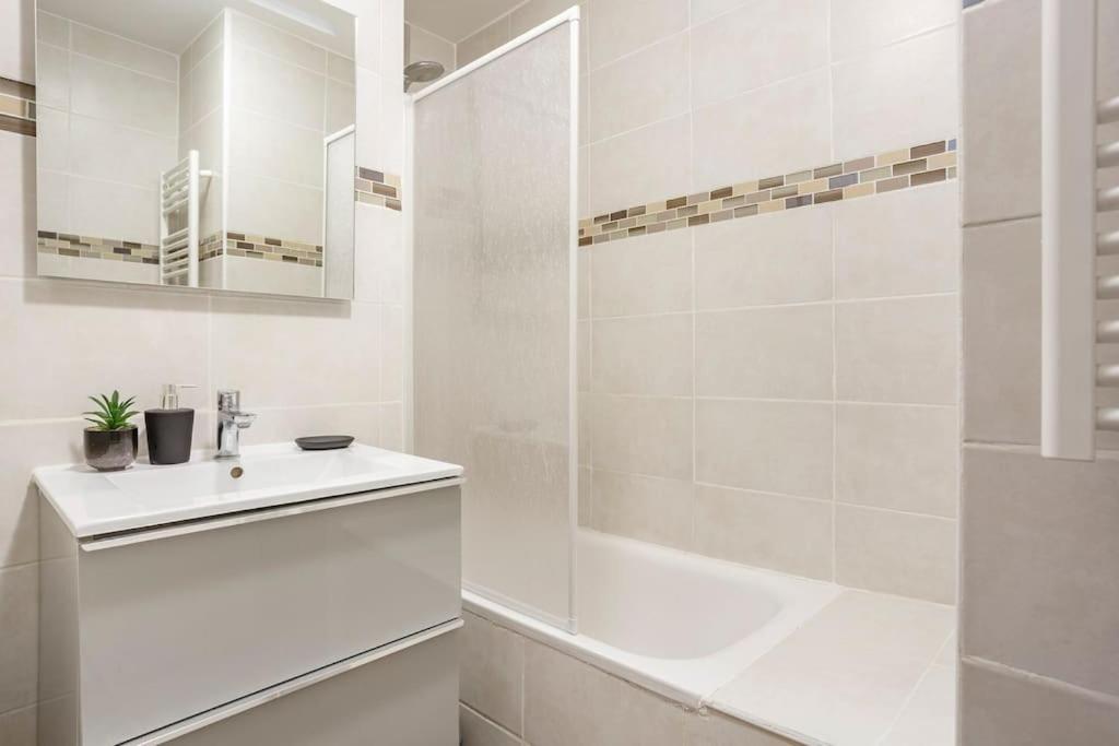 a white bathroom with a sink and a shower at Appart spacieux près de la Seine in Sartrouville