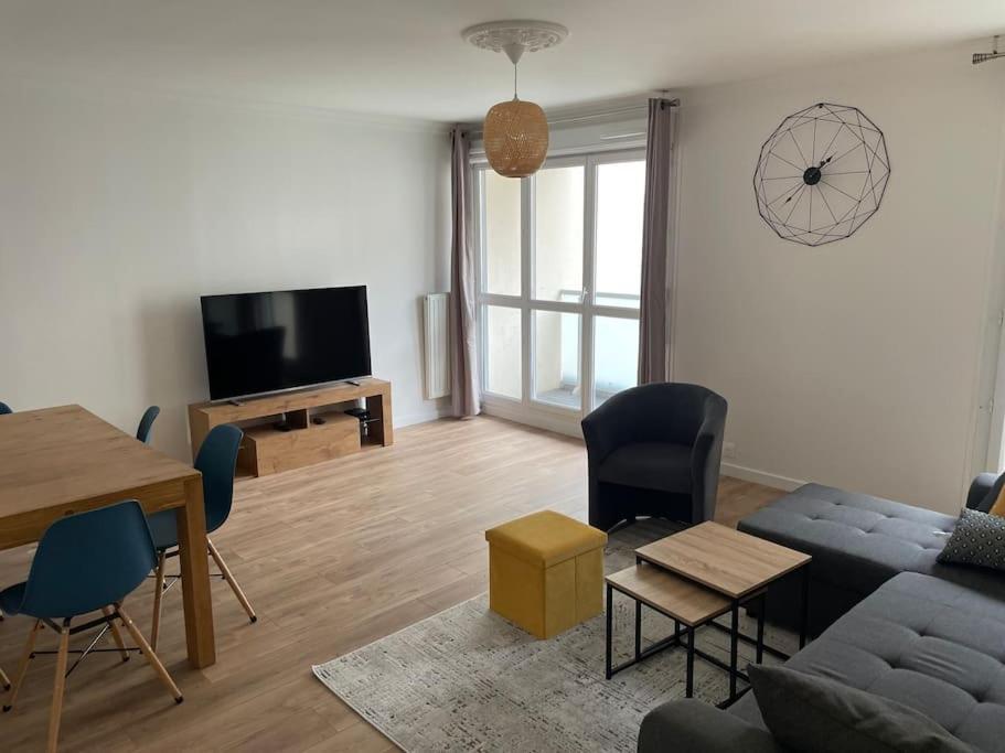 a living room with a couch and a table and a tv at Appart spacieux près de la Seine in Sartrouville