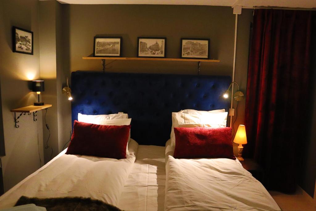 1 dormitorio con 1 cama con almohadas rojas y blancas en Göte`s B&B en Tumba