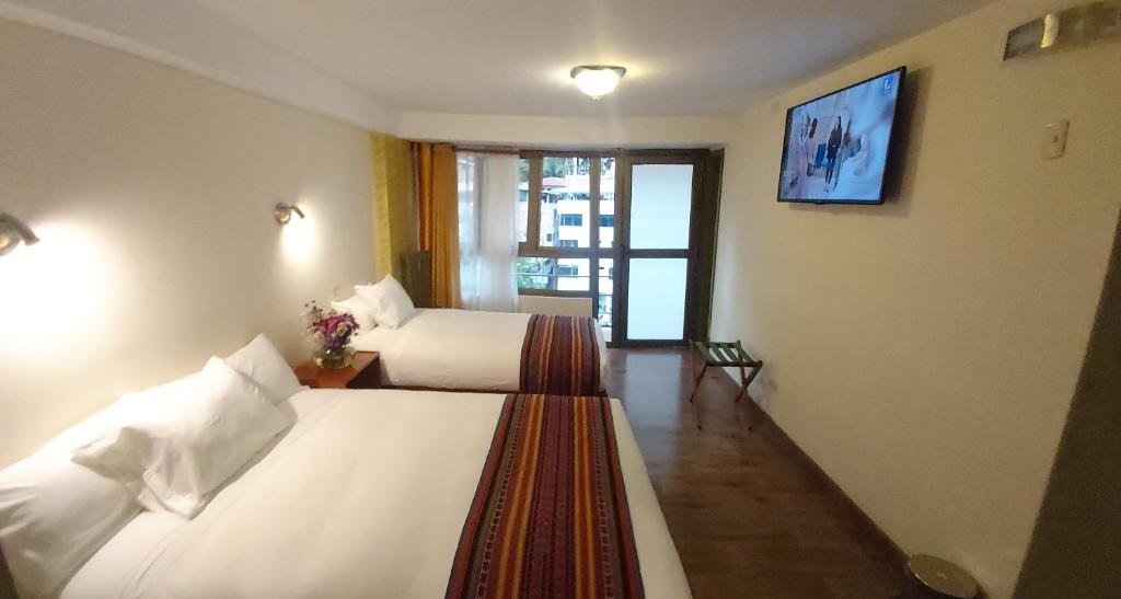 1 dormitorio con 2 camas y TV en la pared en Hotel Pucara Machupicchu, en Machu Picchu
