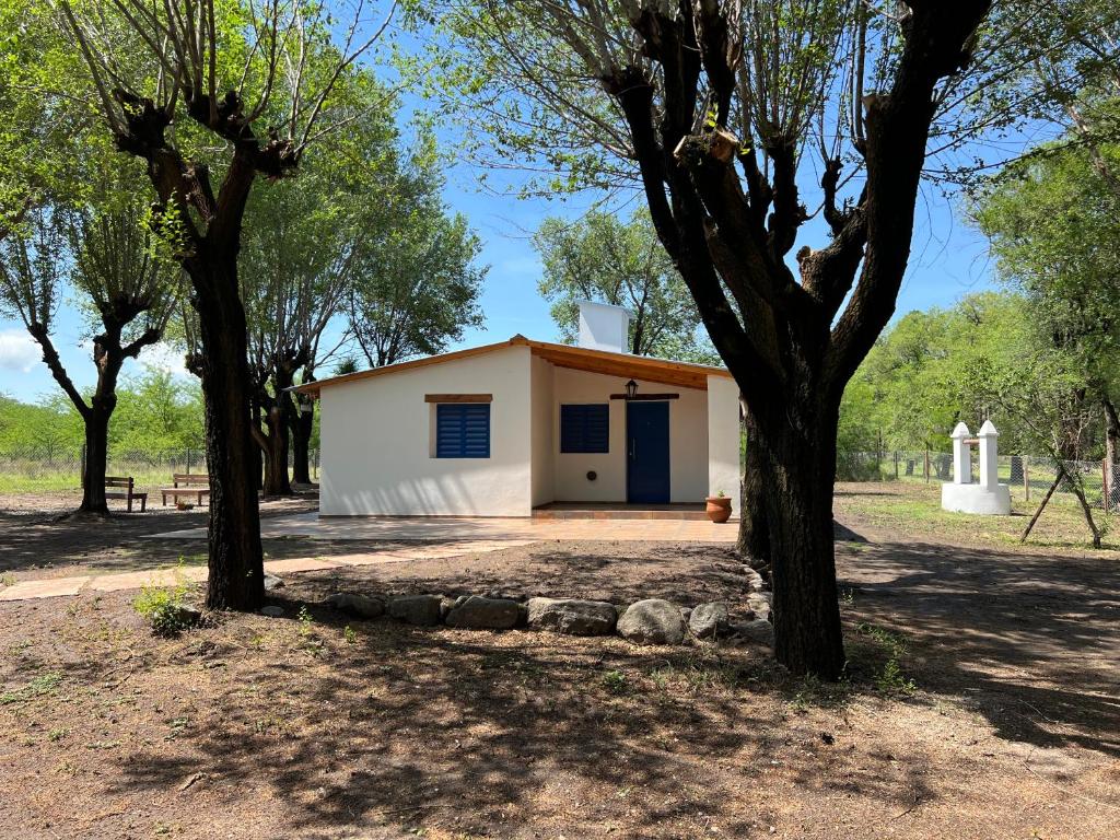 un pequeño edificio blanco con árboles delante en Casa Azul en Santa Rosa de Calamuchita