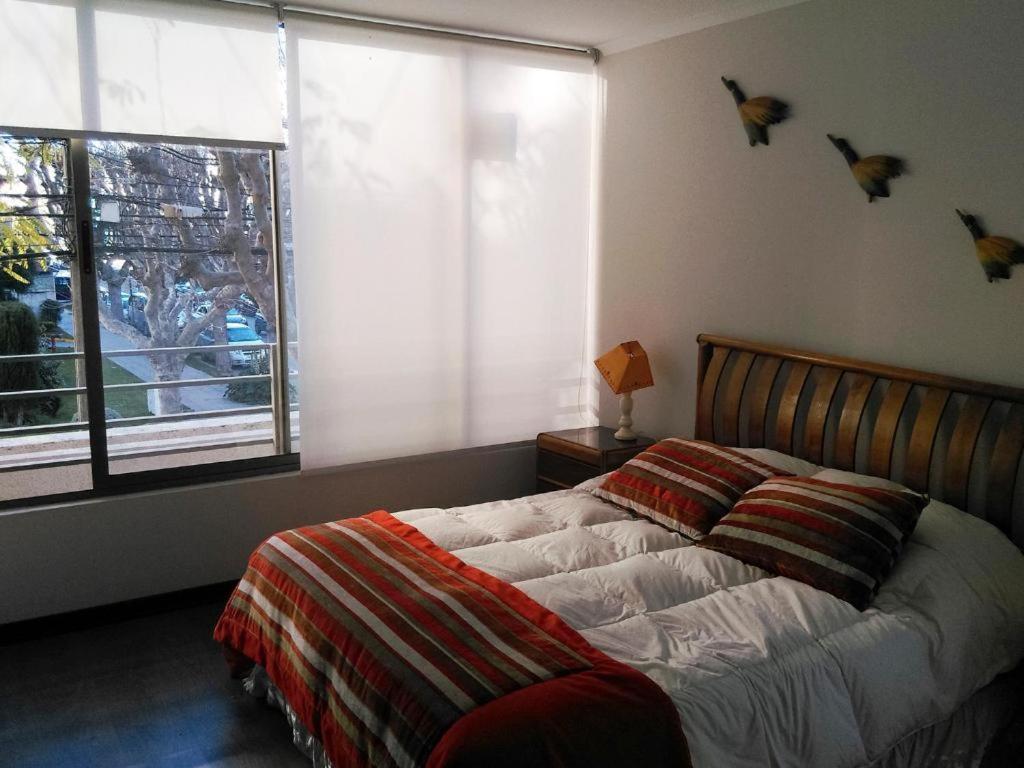 1 dormitorio con cama y ventana con pájaros en la pared en 2 Poniente con 3 Norte HERMOSOS Departamentos, en Viña del Mar