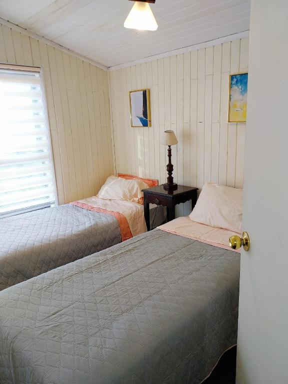 - une chambre avec 2 lits et une fenêtre dans l'établissement Cabañas Don Peto, à Ancud