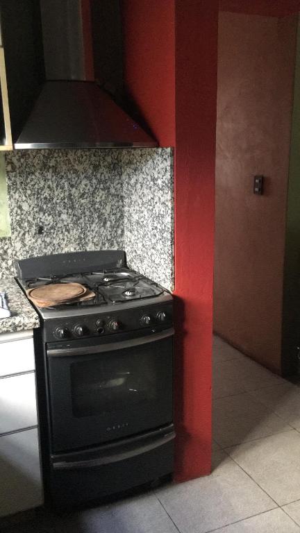 cocina con fogones negros y pared roja en Arroyo en Alta Gracia