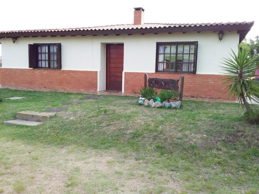 una casa blanca con una puerta roja y algunas plantas en mi sueño, en Punta del Diablo