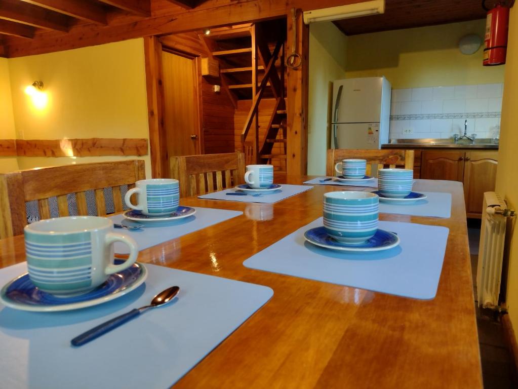 una mesa con tazas azules y platillos en ella en Cabañas El Estribo Sur Bariloche en San Carlos de Bariloche
