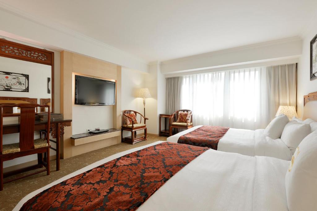 a hotel room with two beds and a flat screen tv at Hotel Sunshine in Kaohsiung