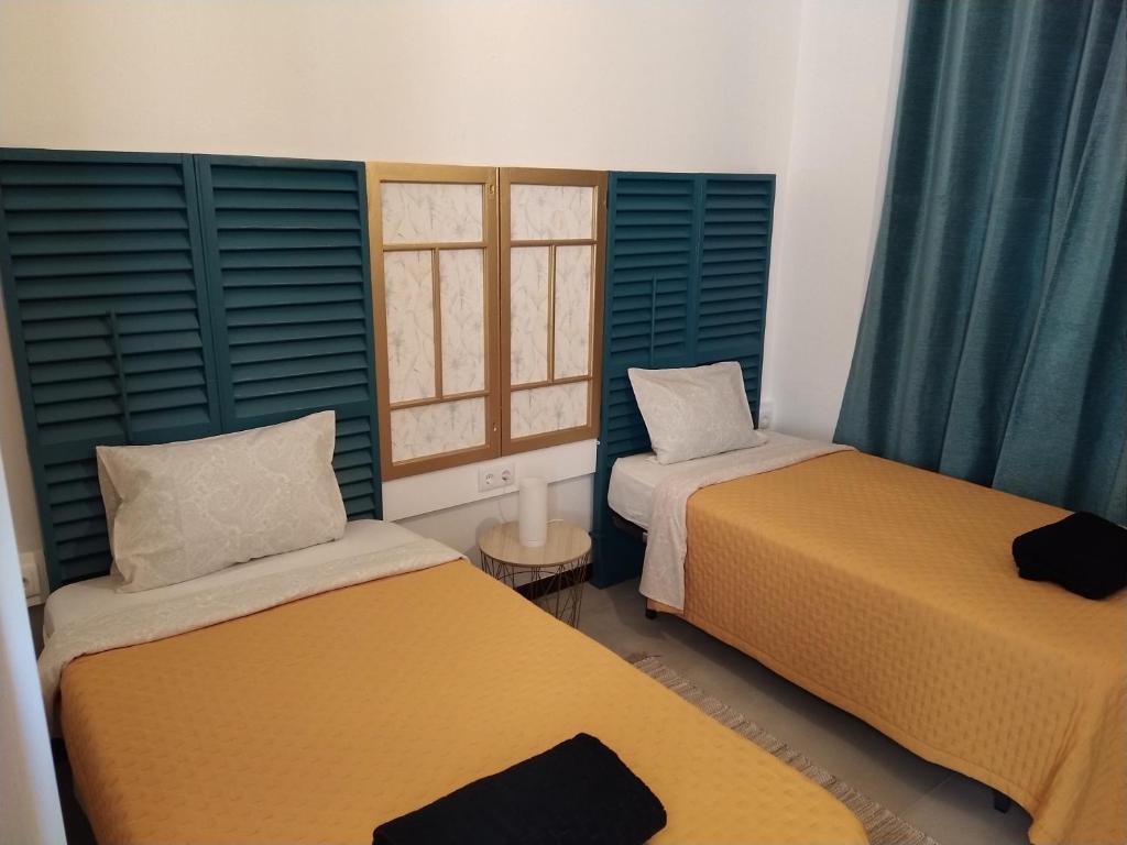 Duas camas num quarto com janelas com persianas azuis em Bus Stop House em Funchal