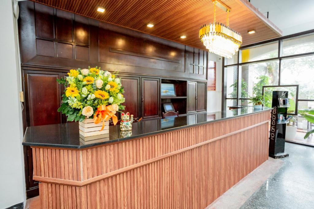 a lobby with a counter with a bouquet of flowers at Sea and Sand Hotel in Hoi An