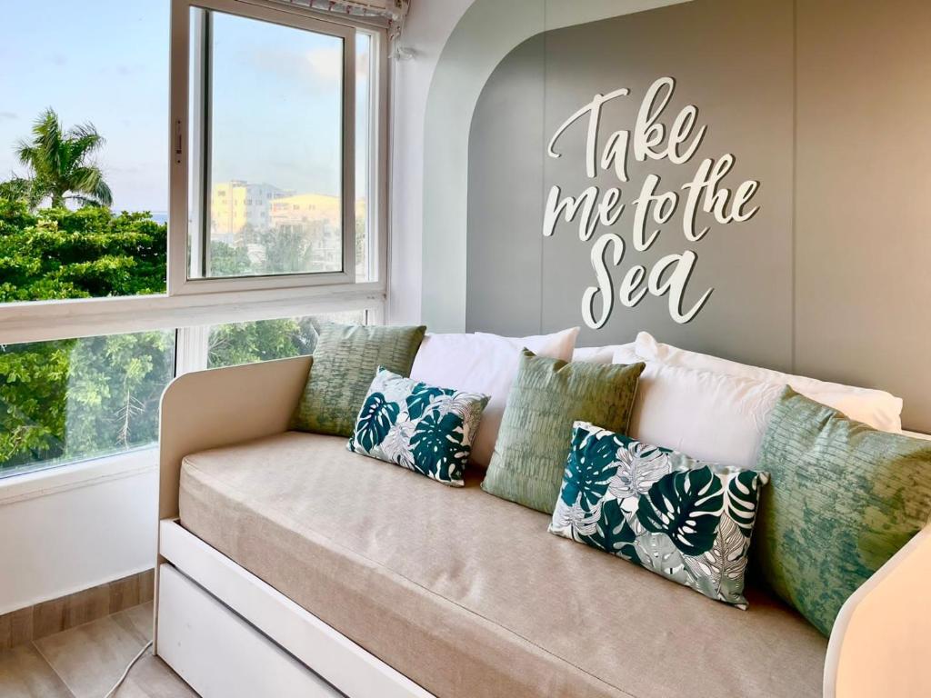 a couch with pillows and a sign that reads take me to the sea at Apartamento Punta Hansa Norte in San Andrés