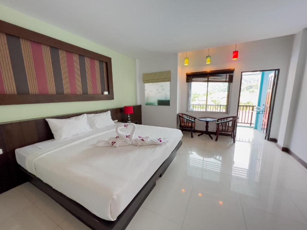 a bedroom with a large white bed and a dining room at Melissa Kata Beach Resort in Kata Beach