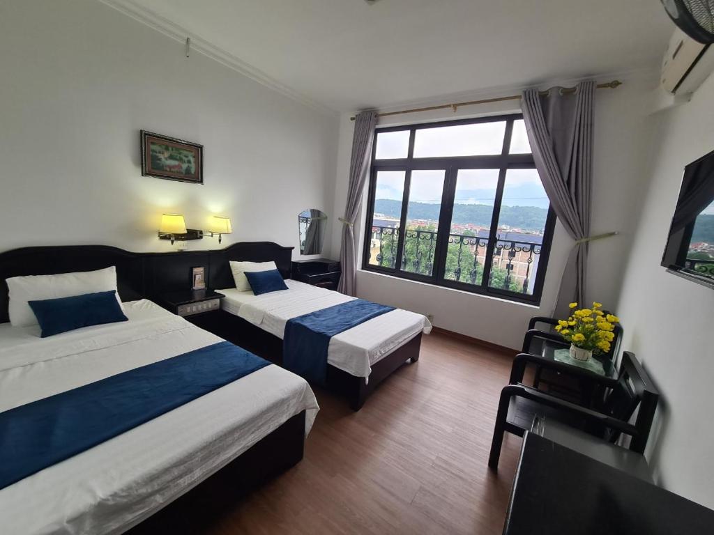a hotel room with two beds and a large window at Khách San Tokyo in Lao Cai