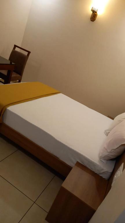 a small bed in a room with a chair at Greenpark Residence in Bangalore