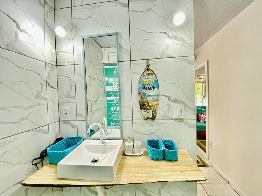 ein Bad mit einem Waschbecken und einem Spiegel in der Unterkunft Casa de Anita Pinheira 30m da praia in Palhoça